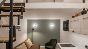 Eine kompakte, moderne Wohnung mit Schlafgalerie, einer Küchenzeile und einem Wohnbereich inklusive Sofa und Sessel.