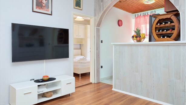 A modern living room with a flat-screen TV, a white entertainment unit, and a wooden floor. - Lima central Old city (Dubrovnik)