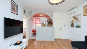 A modern living room with a flat-screen TV, wooden flooring, and a dining area with a red and white checkered tablecloth. - Lima central Old city (Dubrovnik)