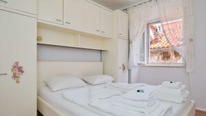 A bedroom with a bed, white curtains, a window, and a wardrobe. - Lima central Old city (Dubrovnik)