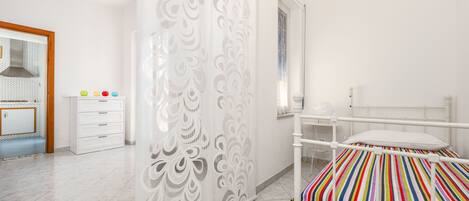 A bedroom with a bed, a dresser, a mirror, and a decorative partition.