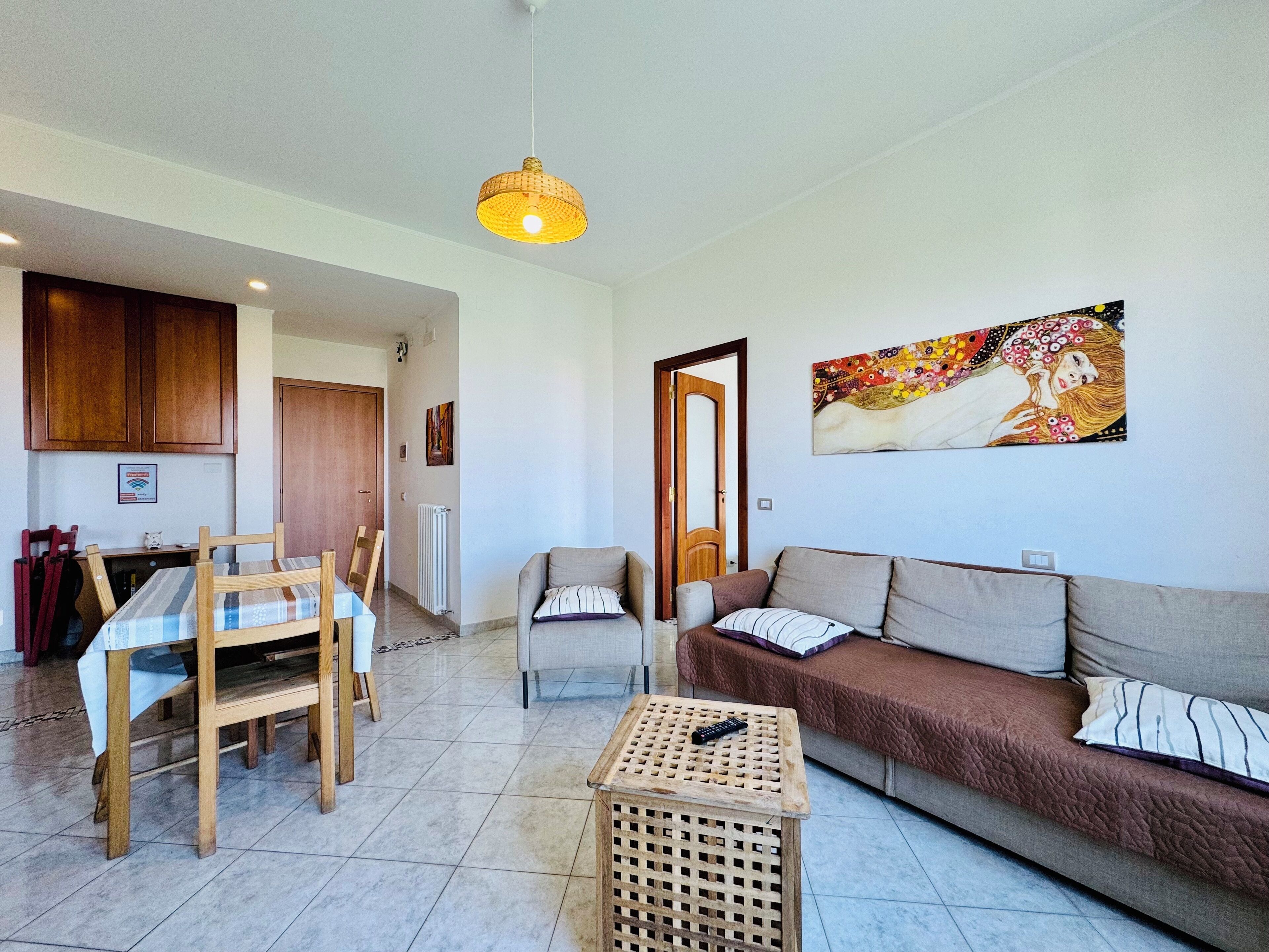 A living room with a sofa, a coffee table, and a dining area with a table and chairs.