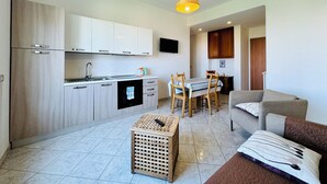 Een ruimtelijk ingerichte leefruimte met kitchenette, eethoek en zithoek.