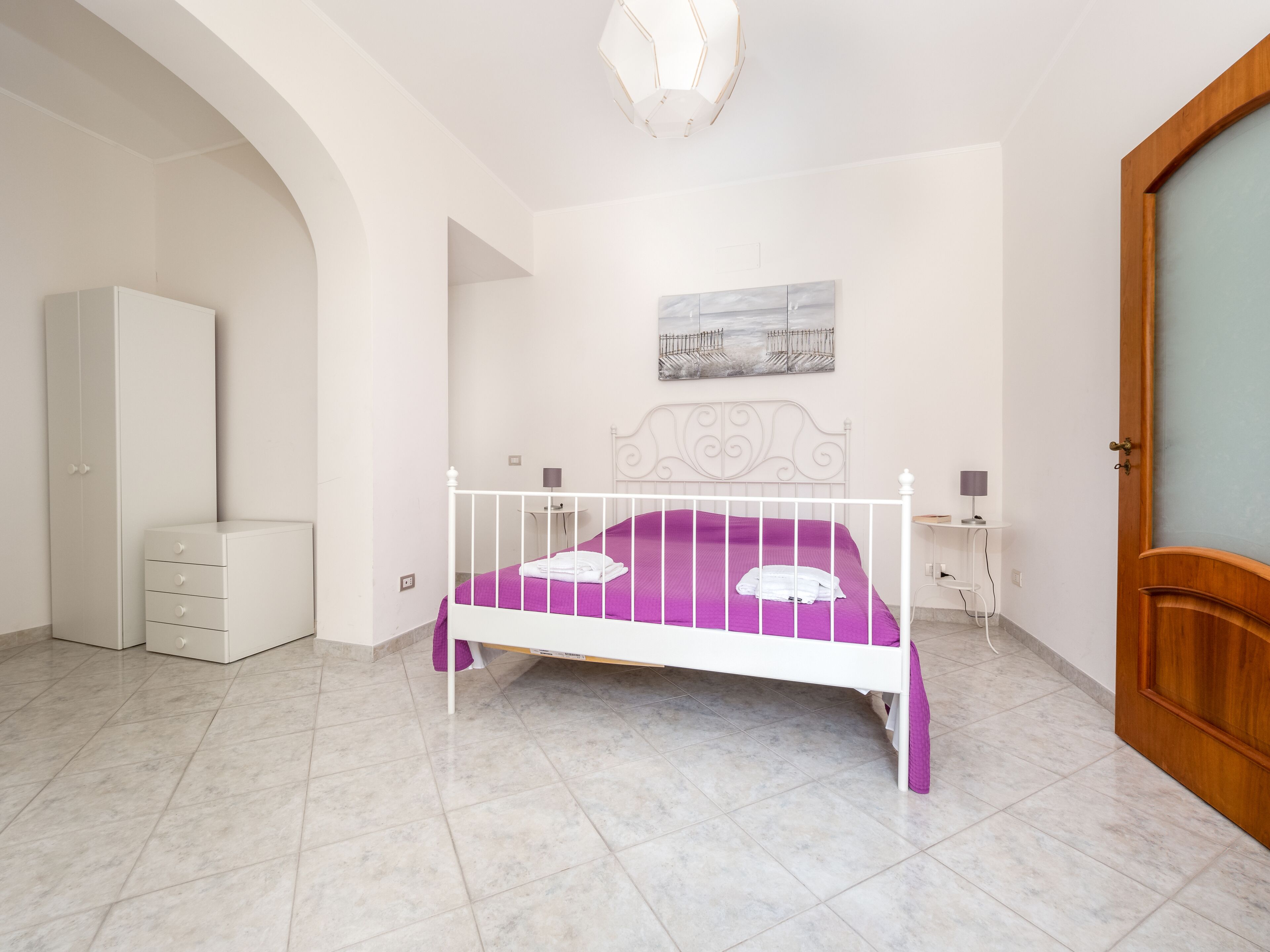 Een slaapkamer met een bed, een kledingkast, een bureau en een deur.