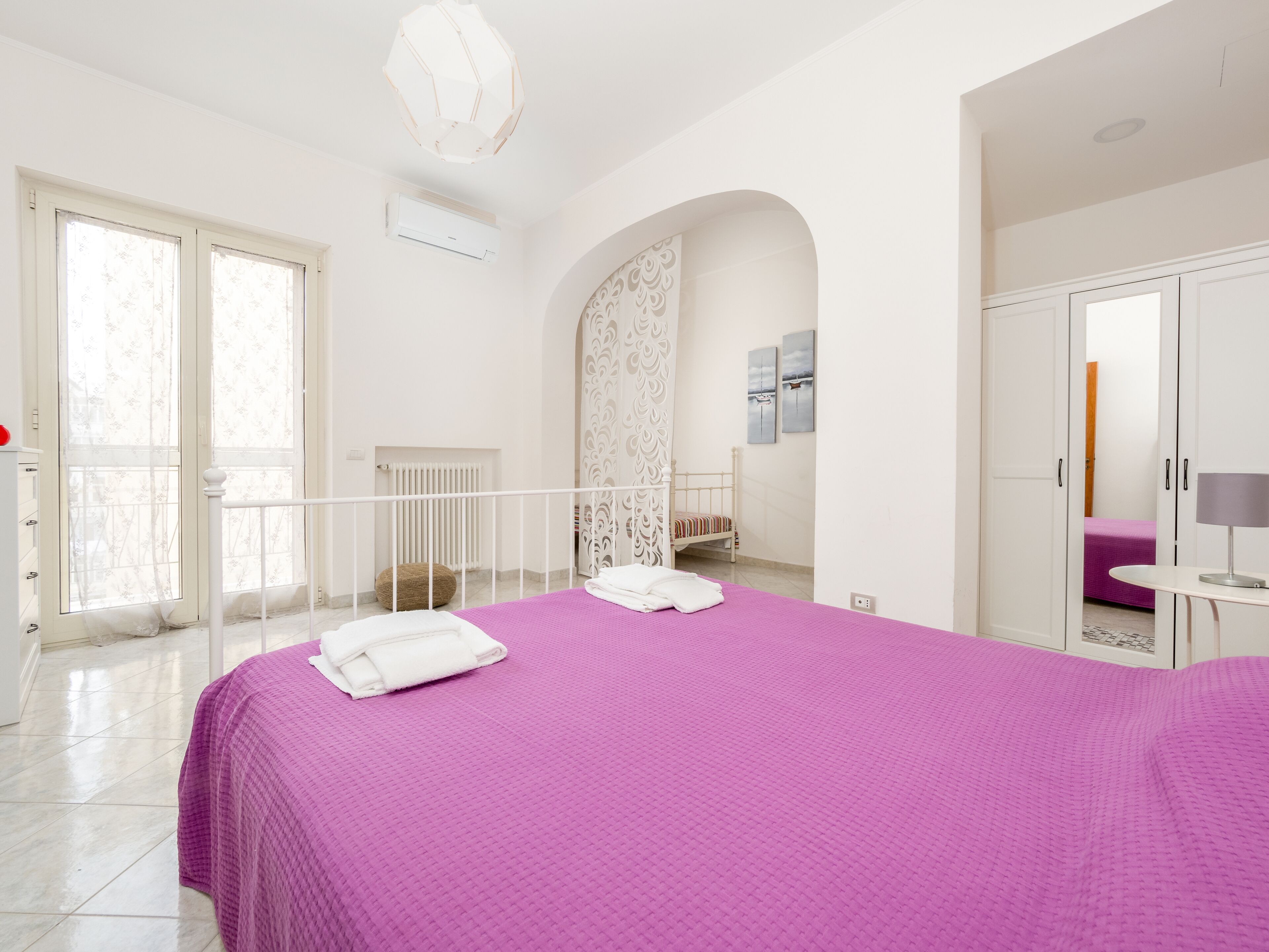 Une chambre avec un grand lit, une armoire, un radiateur et une fenêtre.