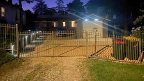 Een hekpoort leidt naar een huis met een kleine schuur.