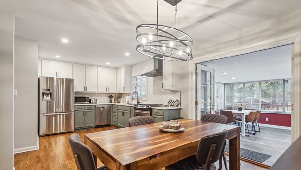 A modern kitchen with stainless steel appliances, a wooden dining table, and a large window offering a view of the outdoors. - Spacious Smyrna Retreat with 3 Kitchens for Groups (Smyrna)