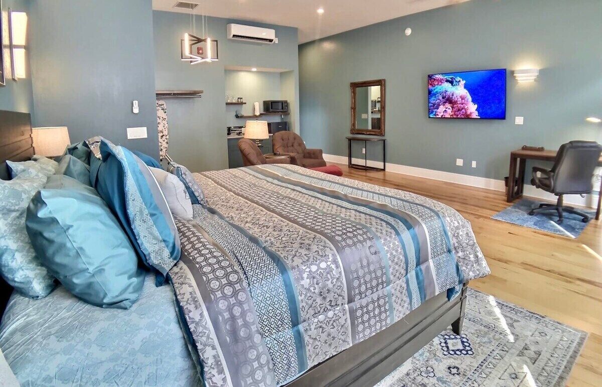 A bedroom with a large bed, a TV, a desk, and a chair.