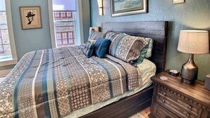Ein Schlafzimmer mit einem Bett, Nachttischen, einer Lampe und Kunstwerken an den Wänden.