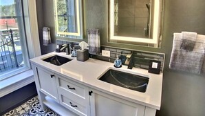 Uma casa de banho moderna com duas pias, um espelho grande e um chuveiro.