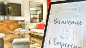 A framed welcome sign with text in French, a candle, and a stone-tiled floor.