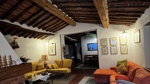 Ein gemütliches Wohnzimmer mit Holzboden, einem gelben Sofa, einem orangefarbenen Sofa und einem gemusterten Teppich.