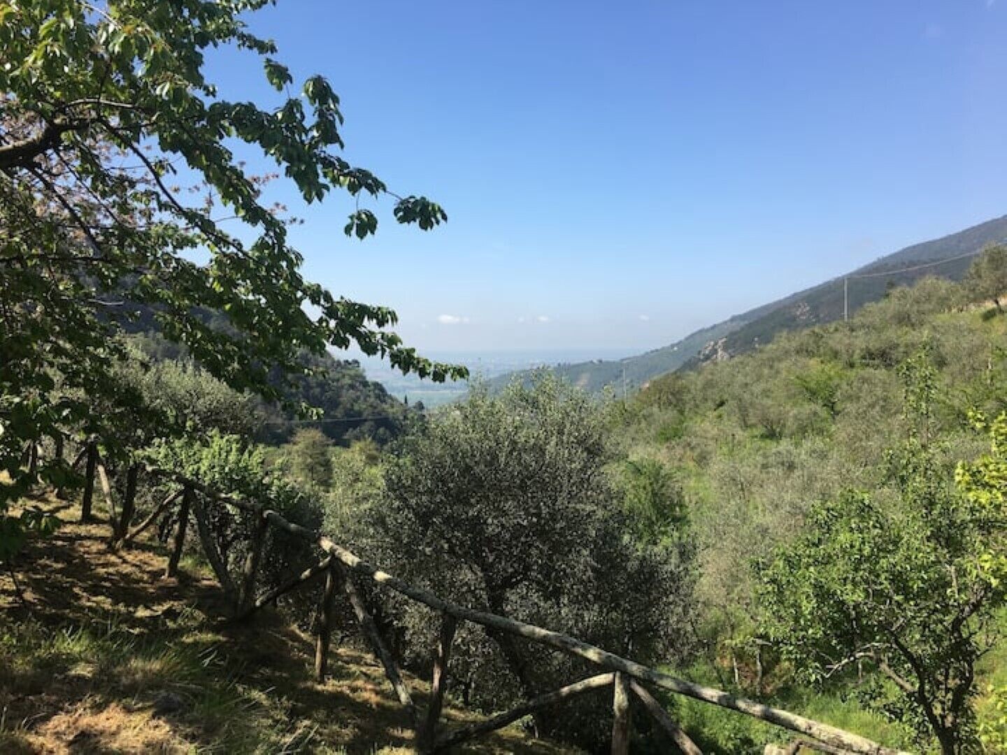 A natural landscape with a clear sky, a view of the valley, and a wooden fence.