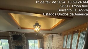 A spacious dining area with a wooden table and chairs, a stone fireplace, and large windows with curtains. - Welcome To Orlando's Chic Cabin! KING BED, FIREPLACE, SAUNA, HOT TUB, GAMES  (Sorrento)
