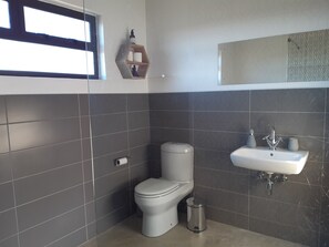 Une salle de bain moderne équipée de toilettes, d’un lavabo et d’une poubelle.