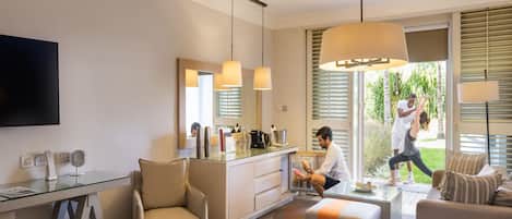 A hotel room with a bed, a desk, a chair, a sofa, and a TV.