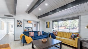 A spacious living room with a blue sofa, yellow sofa, and a dark wooden coffee table. - Stunning 3 bedroom Sedona Home (Sedona)