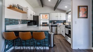 A modern kitchen with a central island, bar stools, white cabinets, and a blue backsplash. - Stunning 3 bedroom Sedona Home (Sedona)