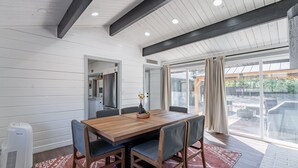 A dining area with a wooden table and chairs, a red patterned rug, and a view of the outdoors through large glass doors. - Stunning 3 bedroom Sedona Home (Sedona)