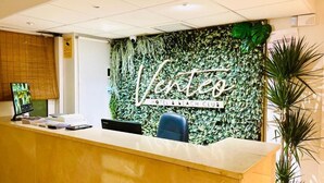 Taulell de recepció amb un cartell de 'Vento Hotel & Beach Club', un ordinador i una cadira.