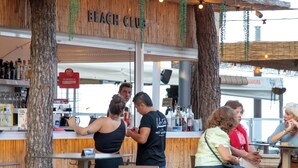 Zona d'estar a l'aire lliure amb una estructura de fusta anomenada "BEACH CLUB".