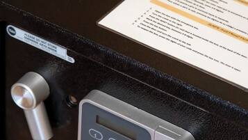 Una caja fuerte con teclado y cerradura, junto a una tarjeta con las instrucciones de uso.