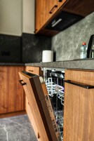 Una cocina con armarios de madera, lavavajillas y encimera.