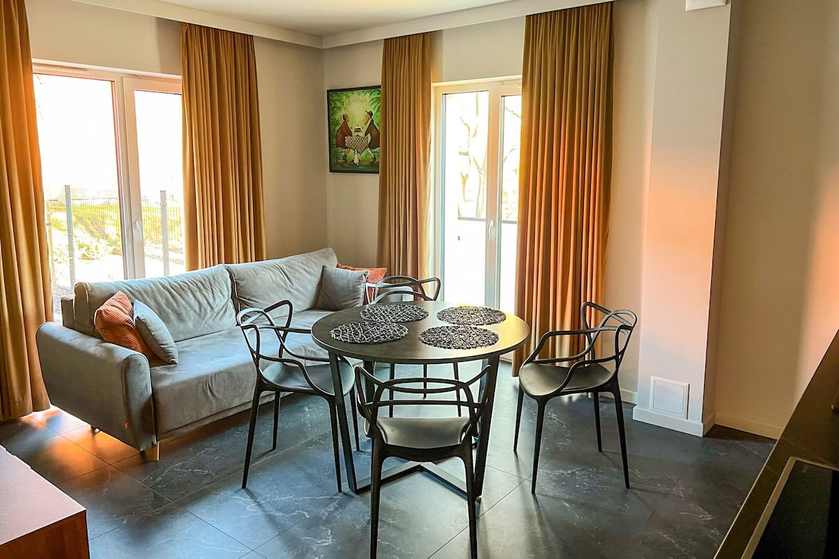 Een moderne woonkamer met een bank, eettafel en stoelen.