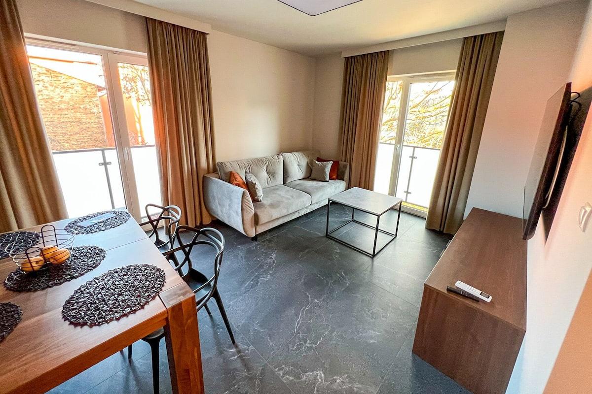Een moderne woonkamer met een bank, een salontafel en een eethoek met een tafel en stoelen.