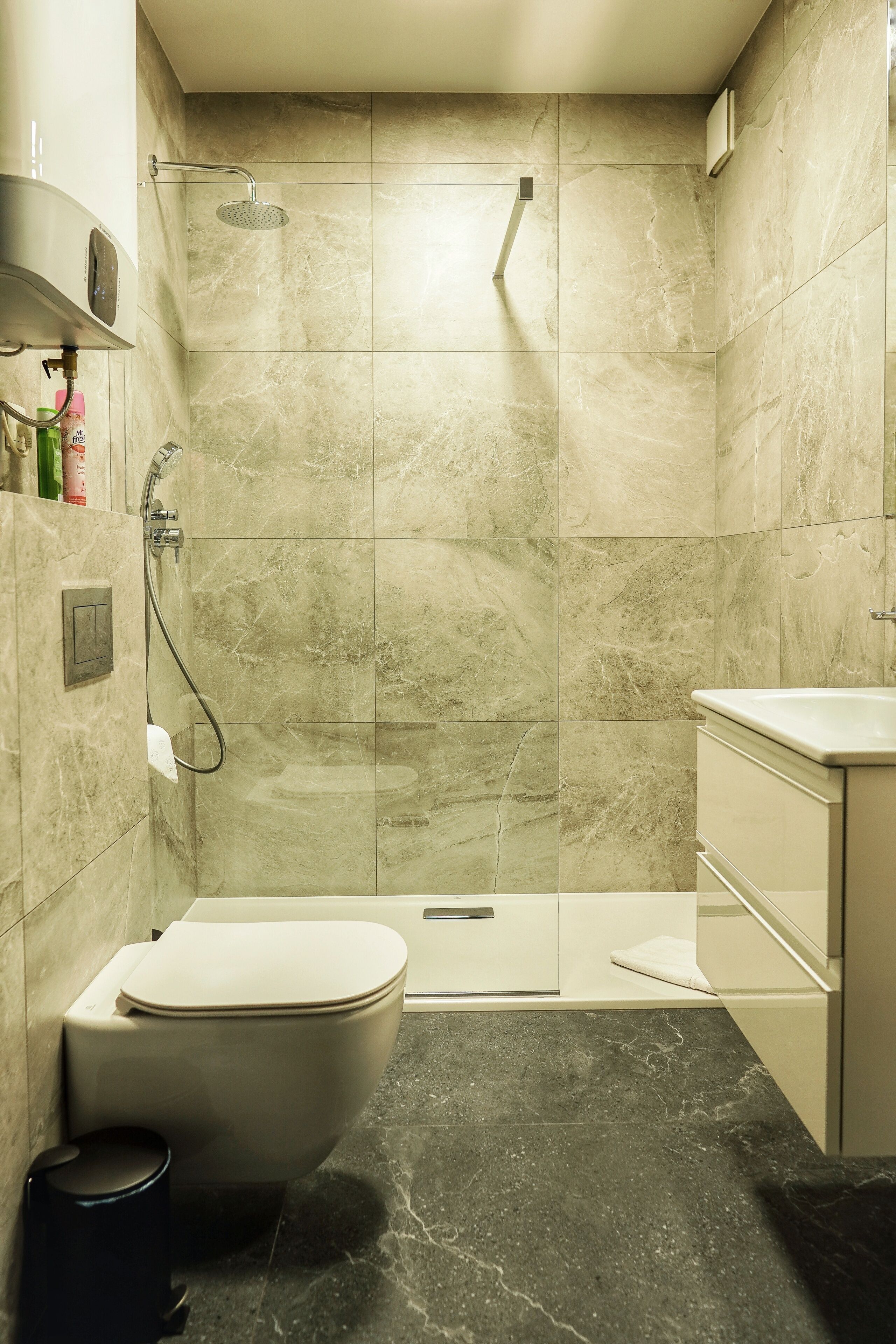 Een moderne badkamer met douche, toilet en wastafel.