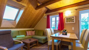 Une pièce confortable de style loft, avec un plafond en bois, un canapé vert, une table en bois et une fenêtre ornée de rideaux rouges.