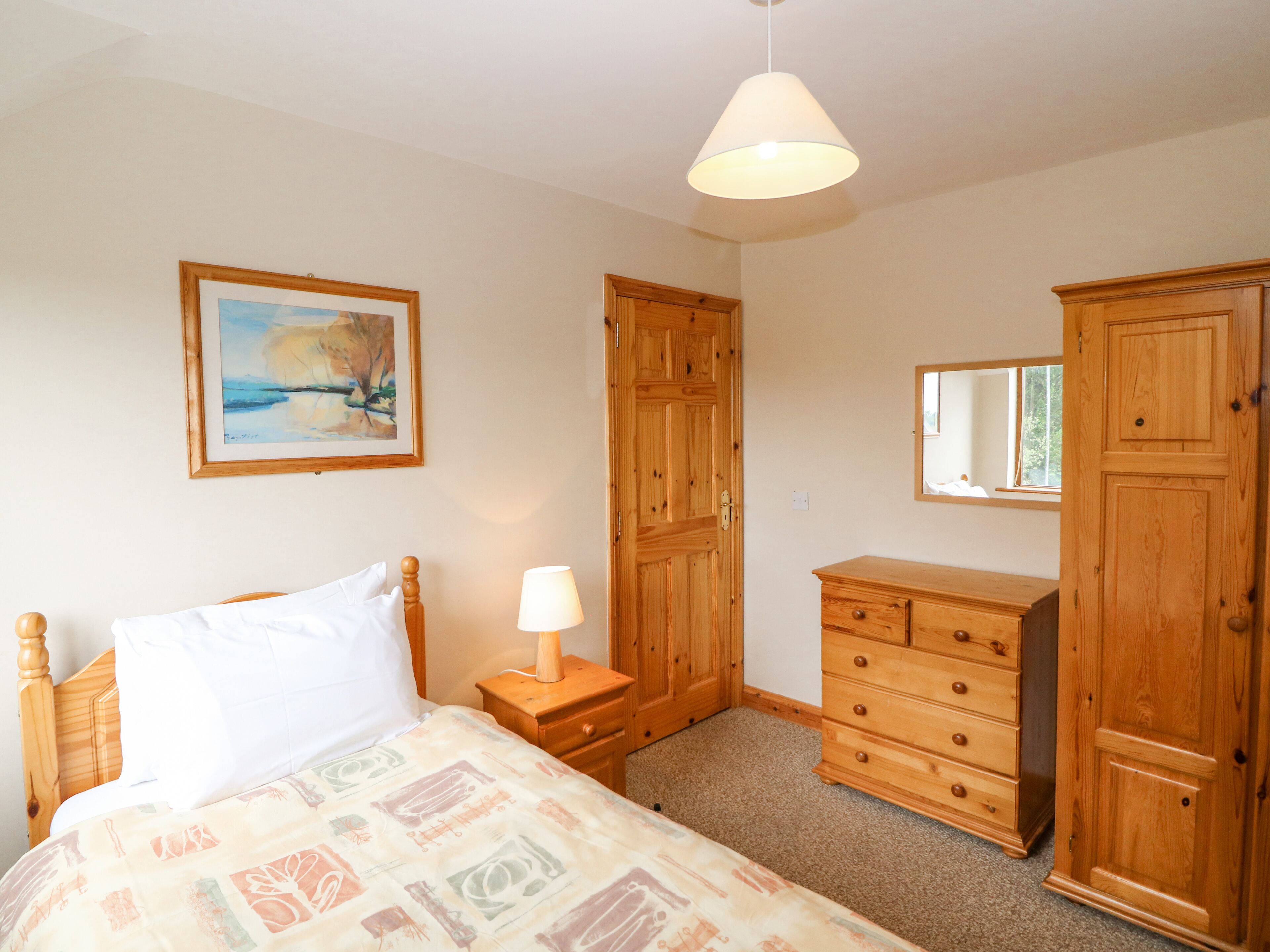 A bedroom with a bed, nightstand, dresser, wardrobe, and a painting on the wall.