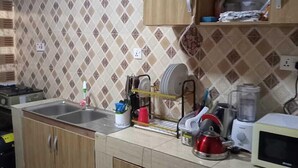 Una cocina con gabinetes de madera, un lavamanos, una estufa y un microondas.