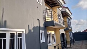 Un edificio de varios pisos con fachada gris, ventanas de marco blanco y un balcón en el piso superior.