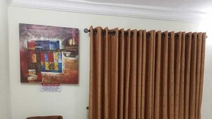 Un comedor con una mesa dispuesta para dos personas, una cortina marrón y un cartel colgado en la pared.
