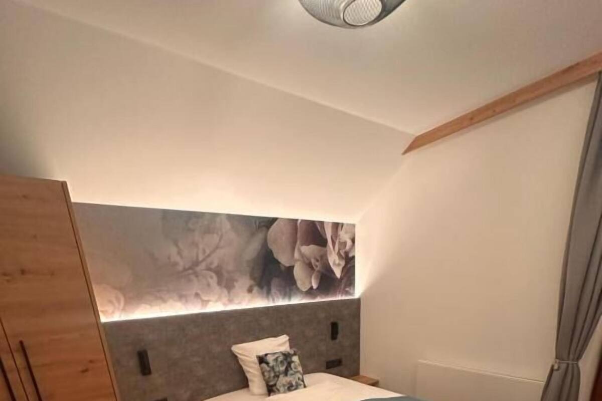 Une chambre à coucher avec un lit, une armoire en bois et un luminaire fixé au mur.