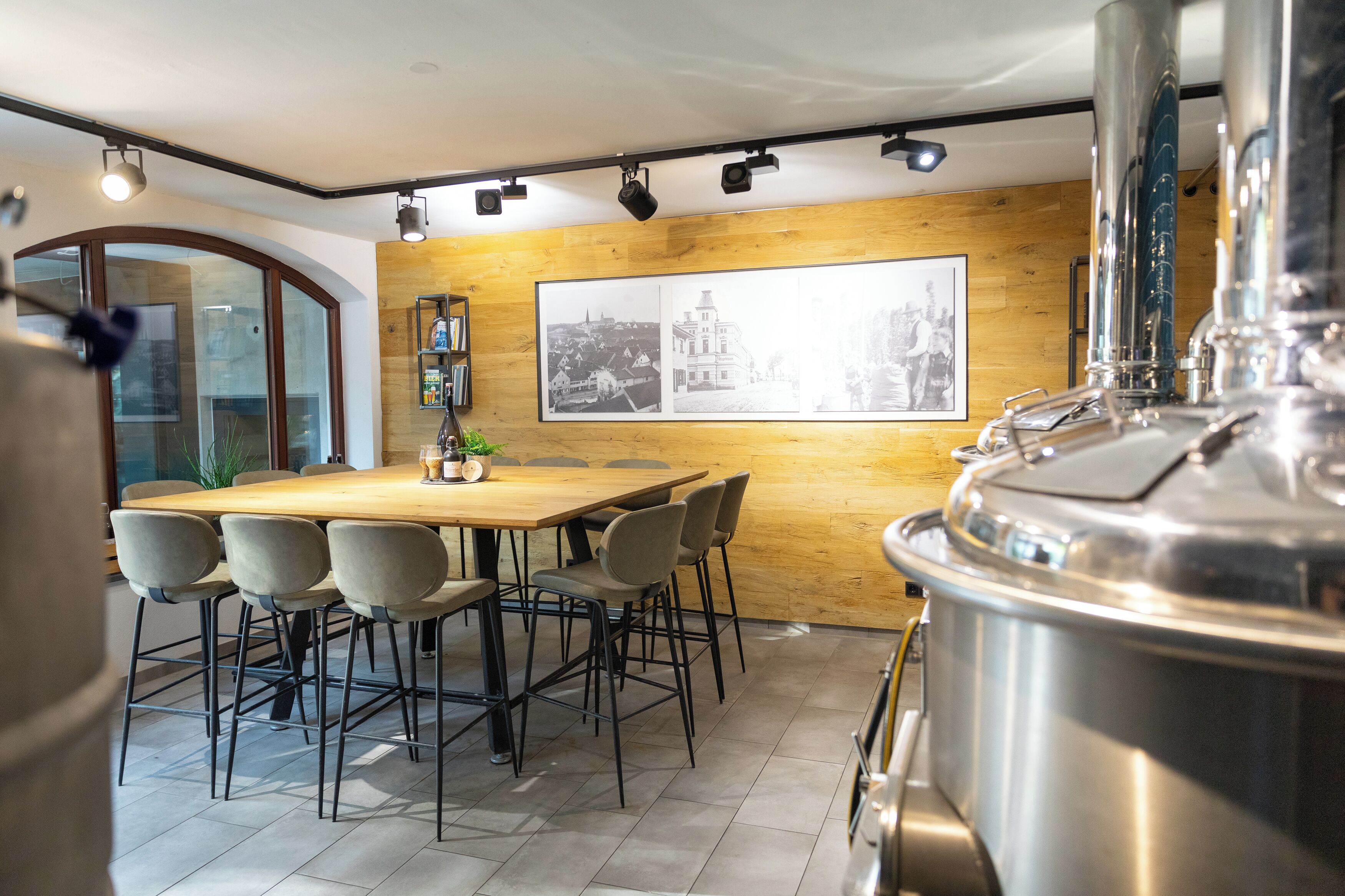 A modern kitchen with a wooden wall, a large window, and a stainless steel brewing setup.