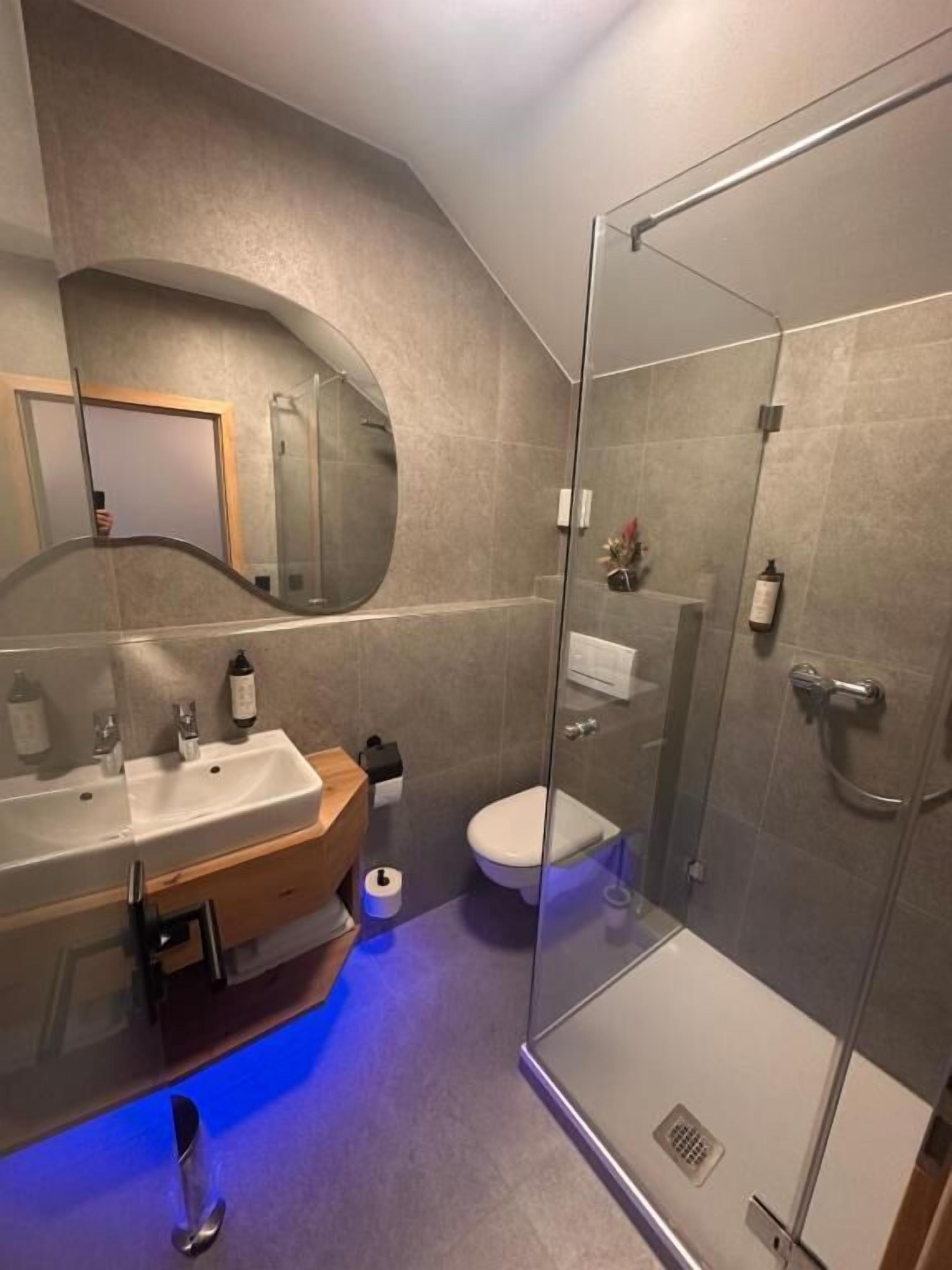 A modern bathroom with a glass shower enclosure, a sink with a mirror, and a toilet.