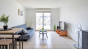 Una sala moderna con sofá, mesa de comedor, televisor y ventilador.