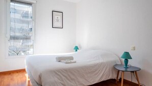 Un dormitorio con una cama, dos mesitas de noche, un ventanal y un certificado enmarcado en la pared.