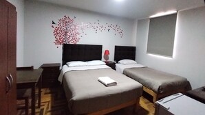 Una camera d'albergo con due letti, una scrivania e una sedia.