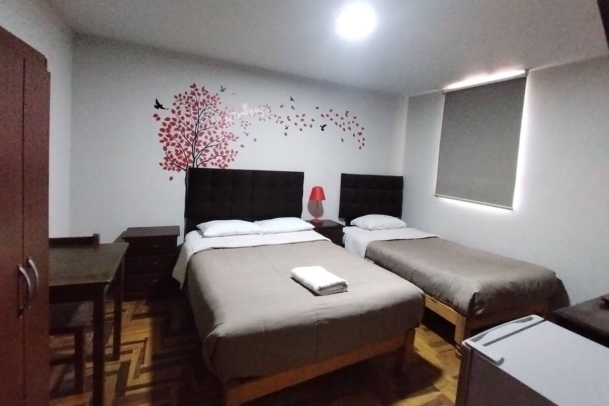 A hotel room with two beds, a desk, and a chair.