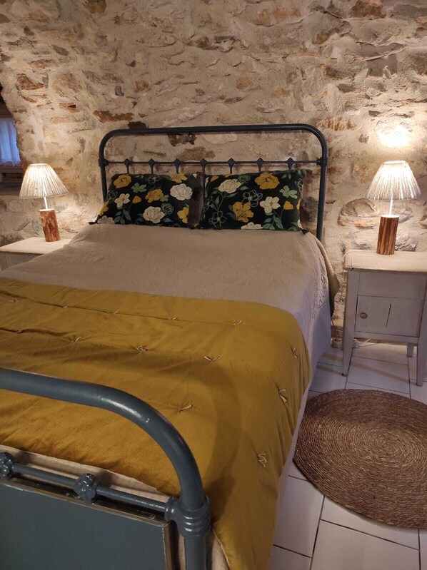 A bed with a metal frame, a headboard with floral pillows, and two bedside lamps on wooden nightstands.