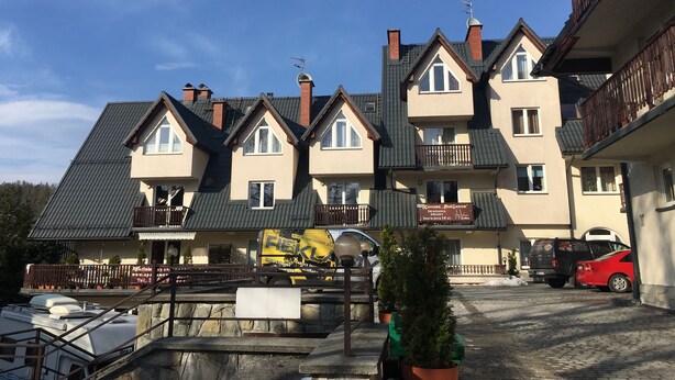Ein mehrstöckiges Wohngebäude mit Satteldach, mehreren Schornsteinen und Balkonen.