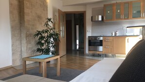 Eine moderne Küche mit Holzausstattung und Edelstahlgeräten, ein Essbereich mit Tisch und Stühlen sowie eine große Pflanze.