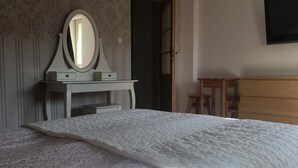 Ein Schlafzimmer mit einem Bett, einem Schminktisch, einem Fernseher an der Wand und einem Schrank.