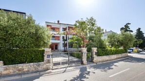 A gated residential area with a stone wall, a metal gate, and a building with balconies. - Apartments Adria (Rovinj)
