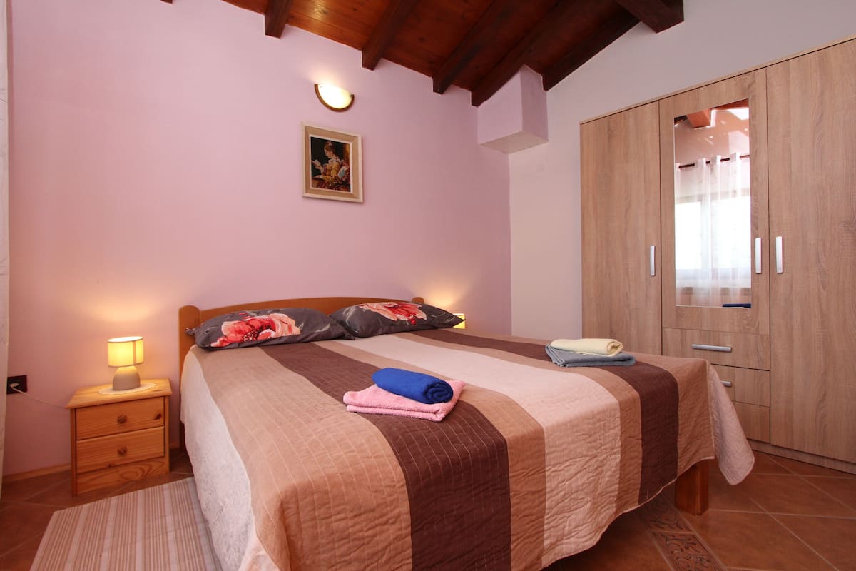 A bedroom with a bed, bedside table, lamp, and wardrobe.