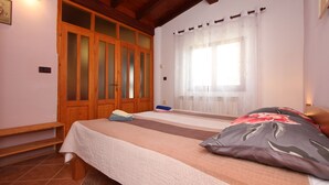 A bedroom with a bed, wooden wardrobe, and a window with curtains. - Apartments Adria (Rovinj)