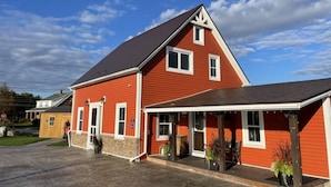 A red building with a covered porch and a garage. - Relax on the South Shore, steps from 2 beaches, ocean views & hot tub. (East River Point)
